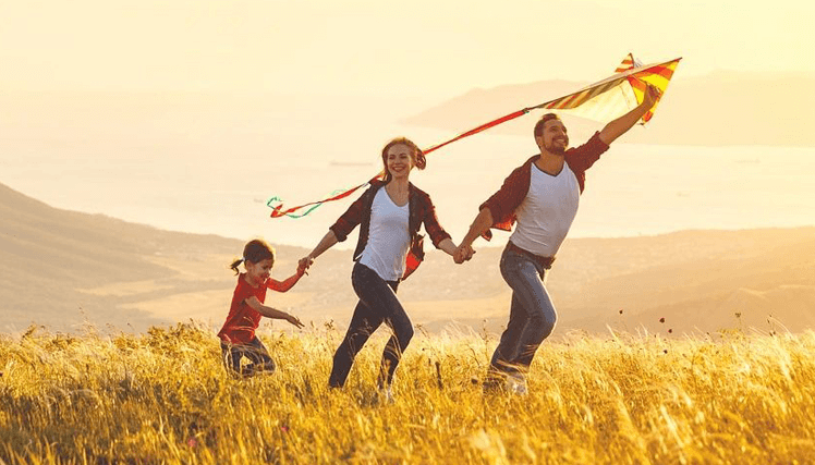 Happy family father, mother and child daughter launch a kite on nature at sunset